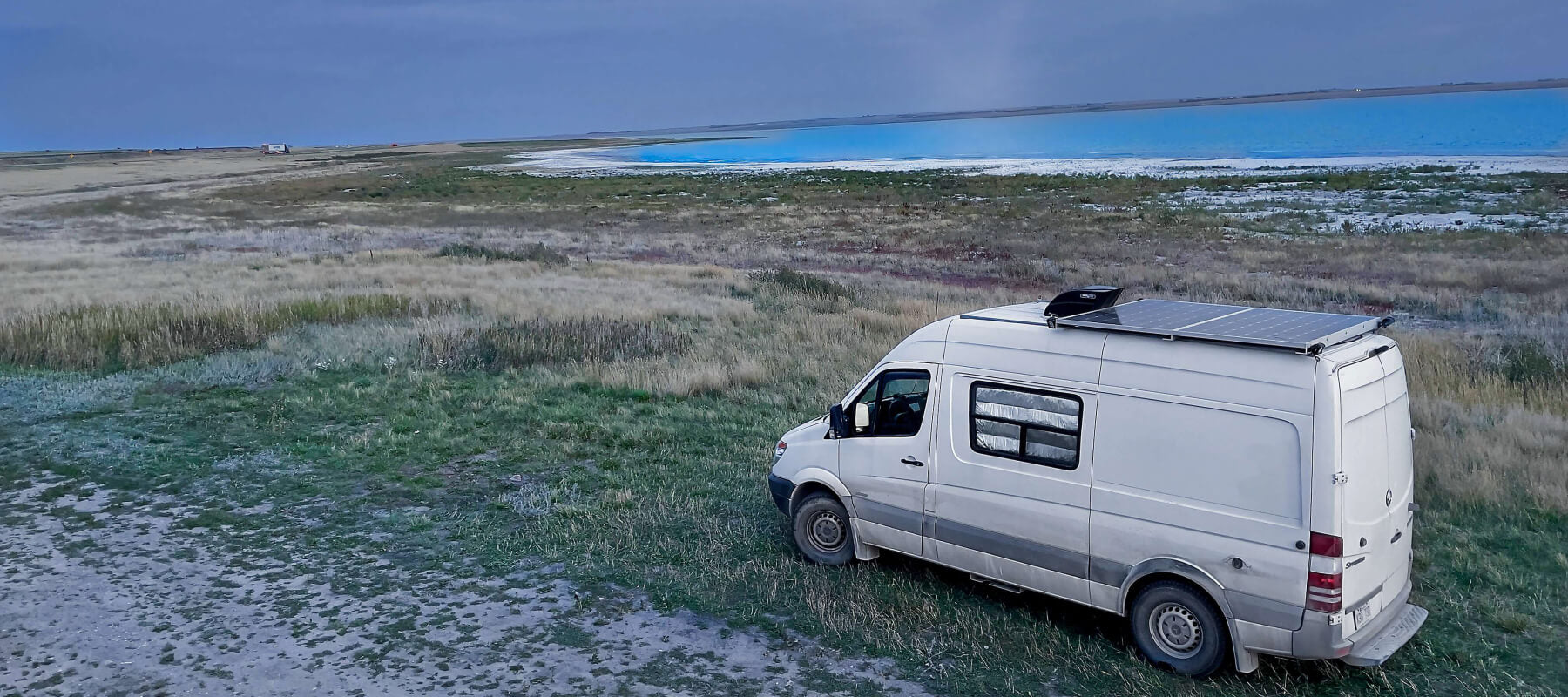 Lonavity eco friendly company, Lonavity van driving at Saskatchewan, beautiful view of the blue water and flat land, solor panels on the van because solar energy is a renewable energy source and reduces carbon emissions