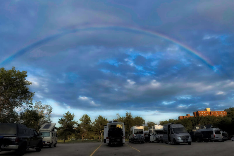 Lonavity, parked in Baie-Comeau, Quebec with other vanlifers, rainbow with blue skies