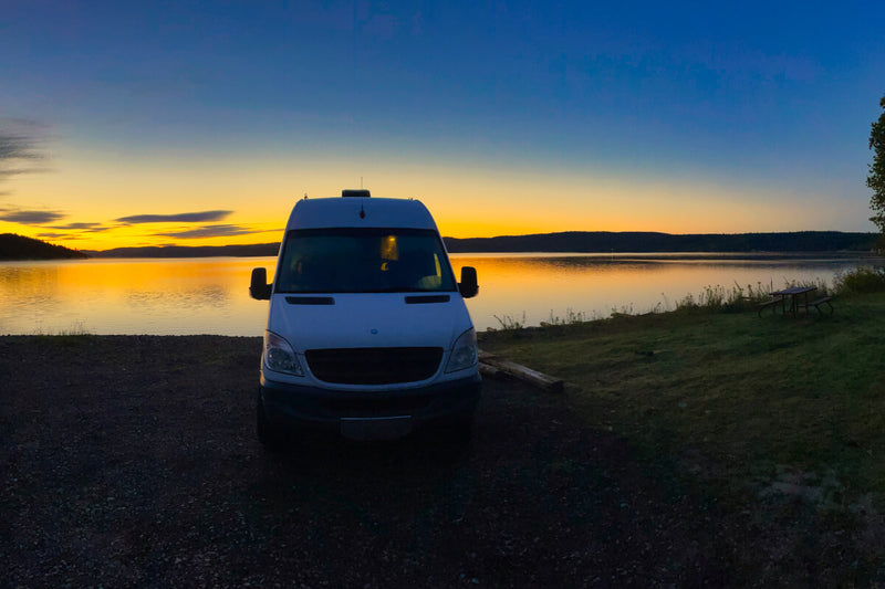 Lonavity van conversion, rent the van for the weekend and explore all the beautiful sunsets in Canada. the sky is blue, orange and yellow, parked by the river and sleeping in the van