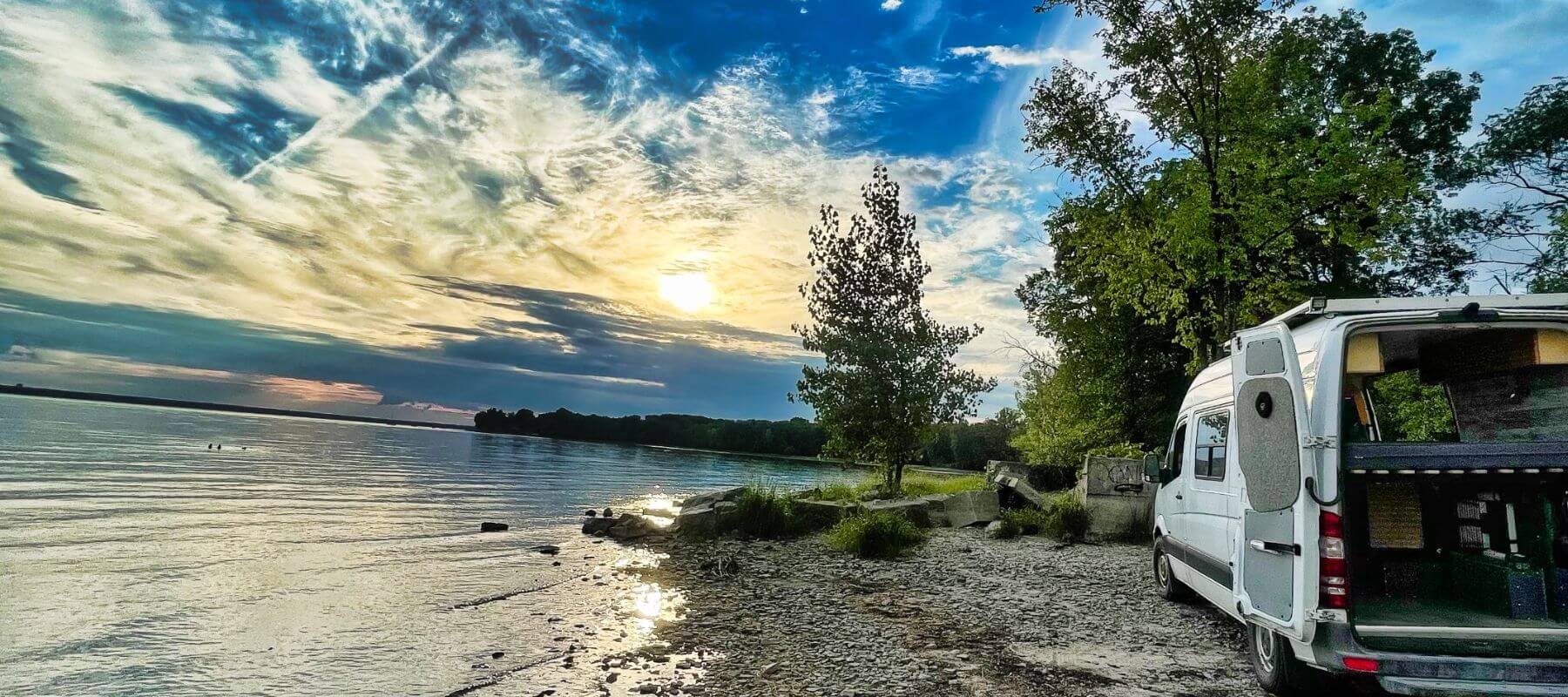 Lonavity van parked by the Gatineau River beach, beautiful sunset