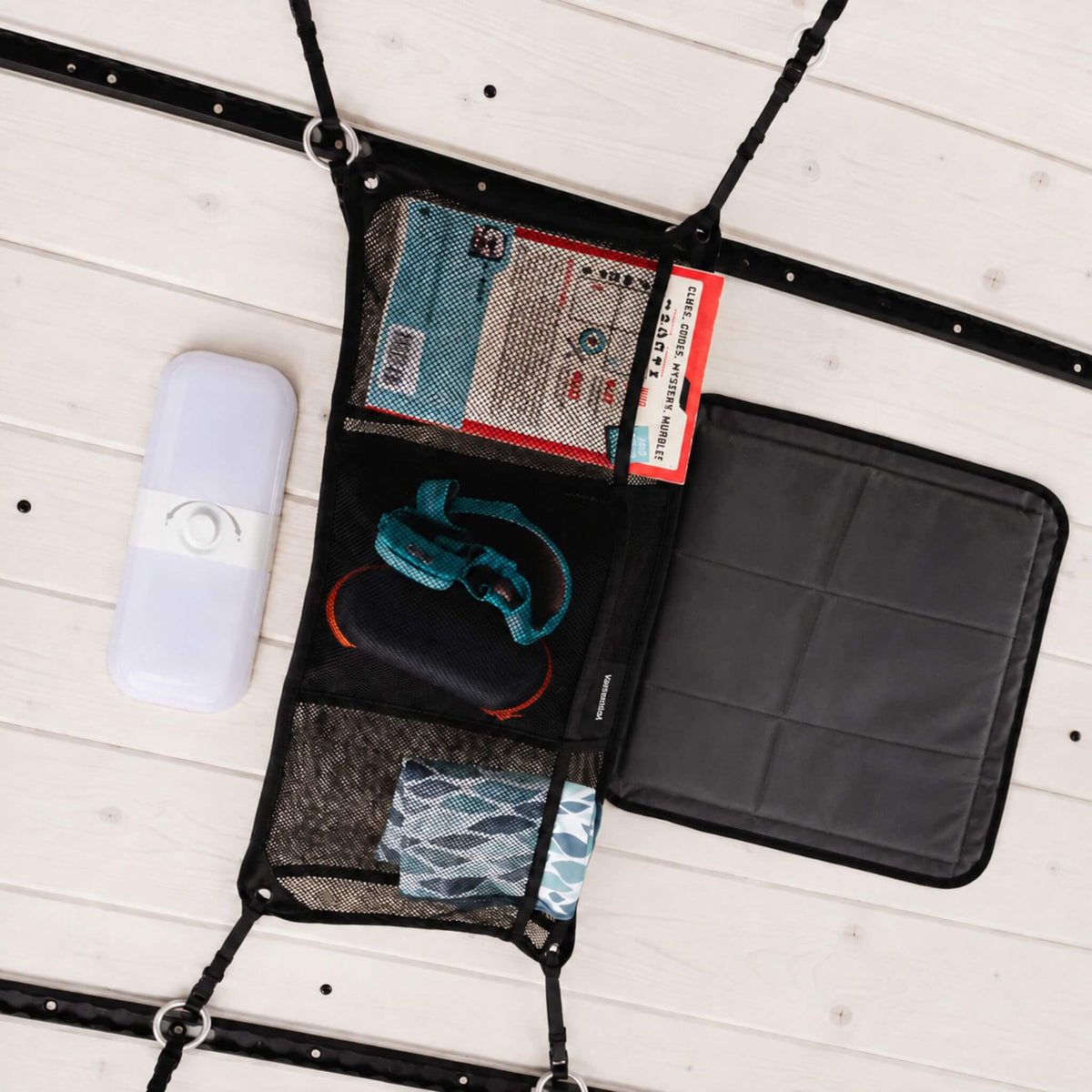 Small double-sided cargo net with six storage pockets for organizing travel essentials in a campervan conversion.