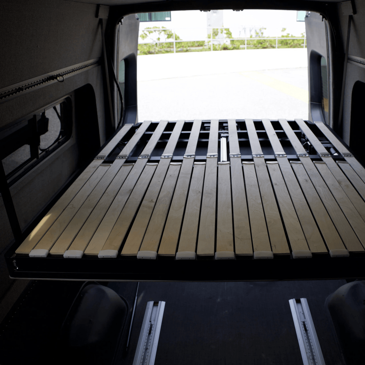 Lift and slide bed system freeing up garage space for vanlife gear