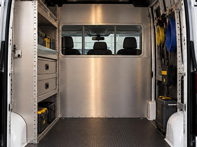 Aménagement de van commerciale Ram ProMaster avec étagères, tiroirs et cloison vitrée pour entreprises de services.