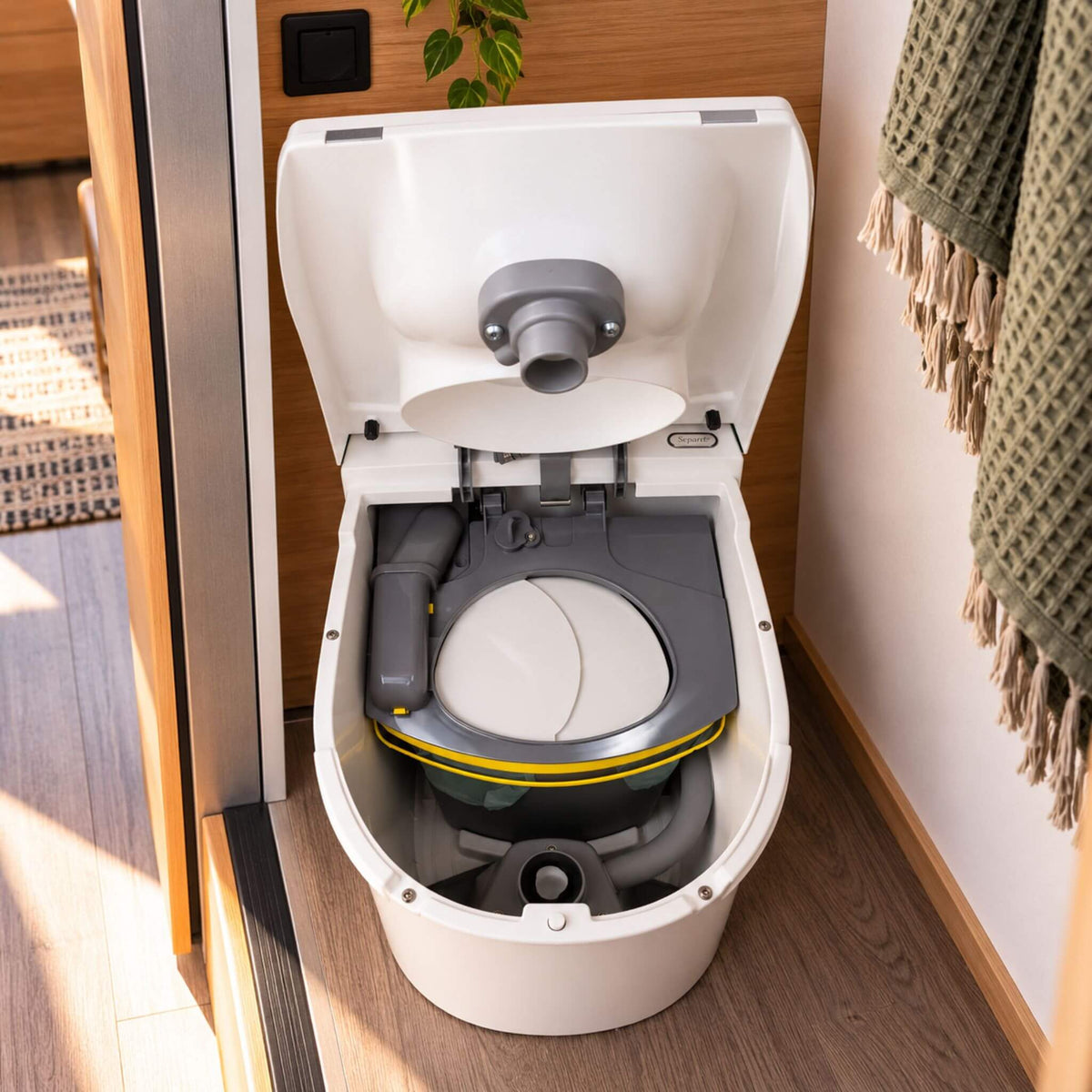 Separett Tiny composting toilet with open solid waste container and removable liner in a campervan bathroom.