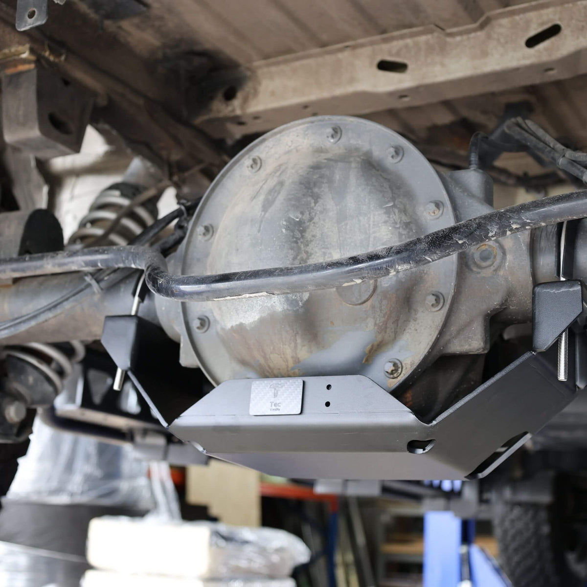 Powder-coated rear differential skid plate mounted under a Sprinter 2500 van, designed to protect against rocks and road debris.