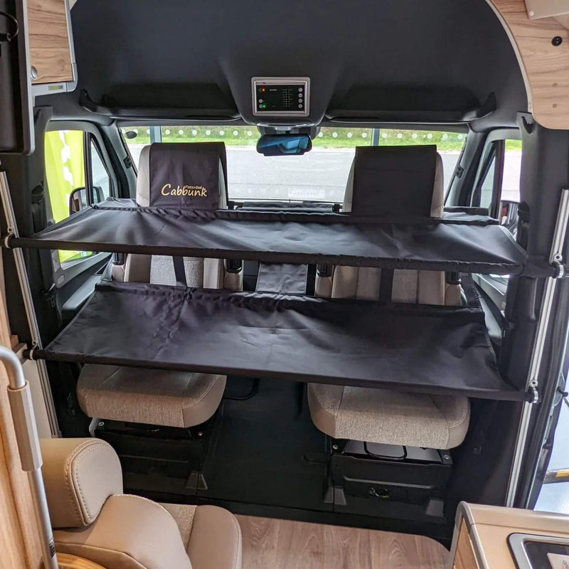 Twin removable bunk beds installed above cab seats in a camper van. / Lits superposés amovibles installés au-dessus des sièges avant dans une fourgonnette aménagée.