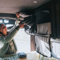 Installing a VanEssential upper storage cabinet on the ceiling L-Track of a camper van.